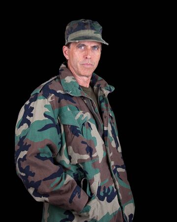 Tough middle aged solider with hands in his pockets isolated on black.の写真素材