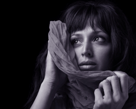 Beautiful young woman holding a shawl to her face.の写真素材
