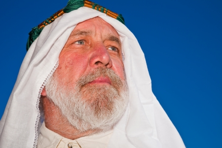 Closeup portrait of an older Arab man isolated against blue sky の写真素材