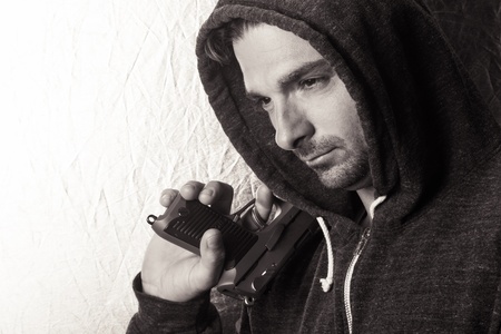 Black and white image of a caucasian male in a hoodie, holding a gun.の写真素材