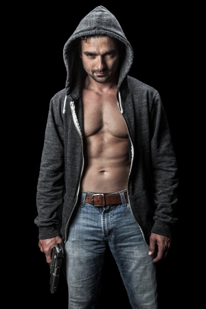 Menacing young man in a hoodie holding a gun の写真素材