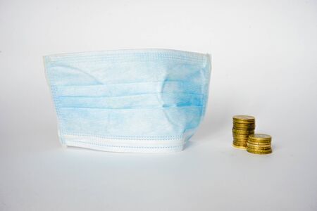 Coins stands near mask, which protect against infection with influenza virus or coronavirus Covid19...