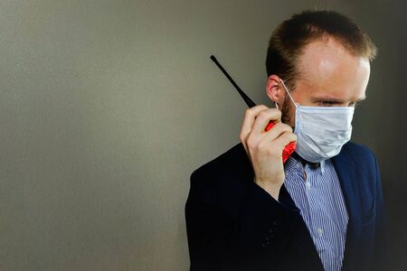 A businessman in a medical mask is talking on the walkie-talkie.の写真素材