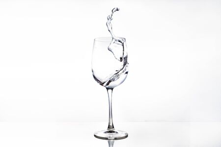 Horizontal photo of a splash of water in a glass for wine. Object isolated on a white background.の写真素材