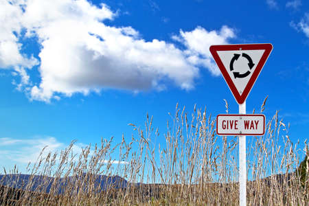 Traffic sign over dry grass and blue skyの写真素材