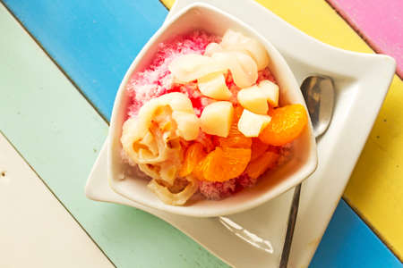 Bowl of fruits dessert with ice on colorful wooden tableの写真素材