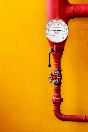 Water pressure gauge of the fire extinguisher with red water pipe on wall