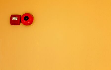 Fire alarm bell and red box warning machine on yellow wall background