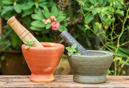 Mint herb leaf in granite and clay mortar with pestle on wood with nature backgroundの写真素材