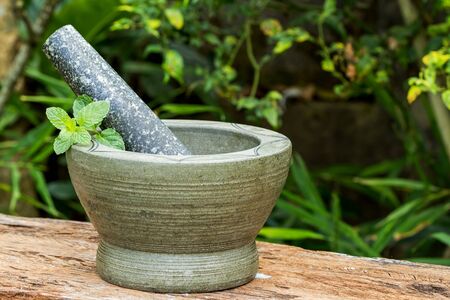 Mint herb leaf in granite mortar with pestle on wood with nature backgroundの写真素材