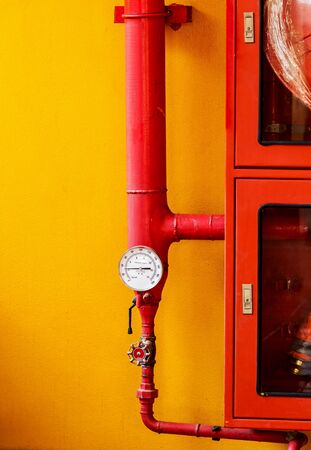 Water pressure gauge of the fire extinguisher with red water pipe on wall