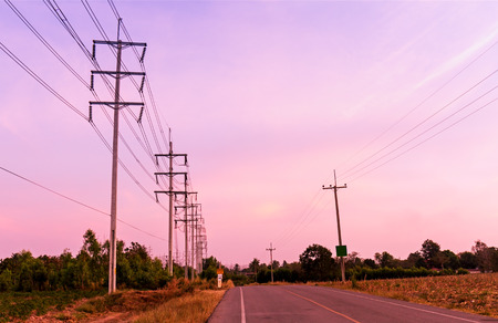 Electrical pole on side the country road at sunsetの写真素材