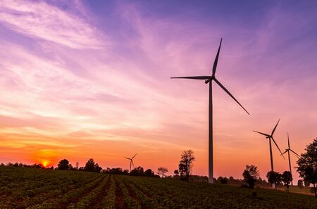 Wind turbines power generator on sunset at farmer fieldの写真素材