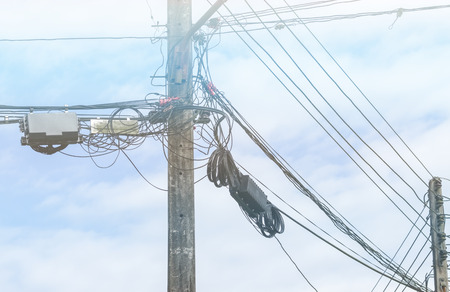 Electrical power pole with power cable and telephone cable against cloud sky
