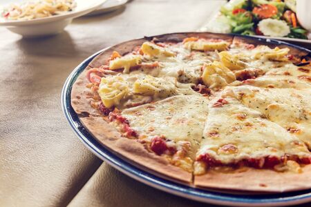 Fresh baked pizza hawaii and sliced on plateの写真素材