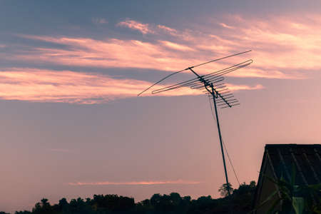 Outdated analogue TV antenna aerial against sunset sky