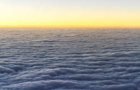 Top view of fluffy white clouds flying on sunset sky view from flying airplane