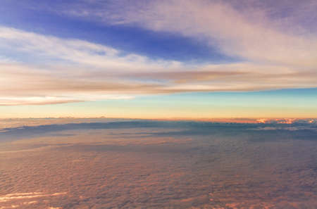 Top view of fluffy clouds on sunset sky view from flying airplane