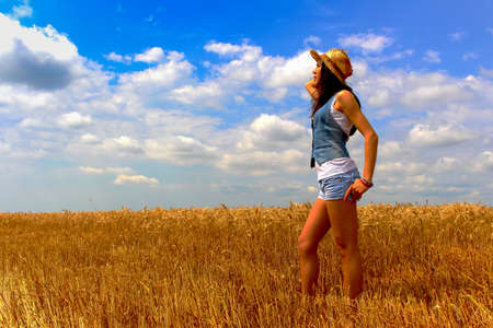 Beautiful woman in rye field on the blue sky