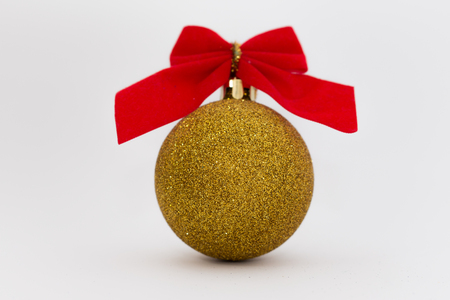 Gold shiny Christmas ball with red ribbon isolated on white background.の写真素材