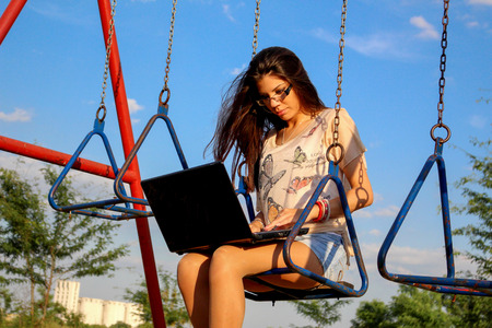 Woman on swing with notebookの写真素材