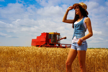 Woman in rye field in front of combineの写真素材
