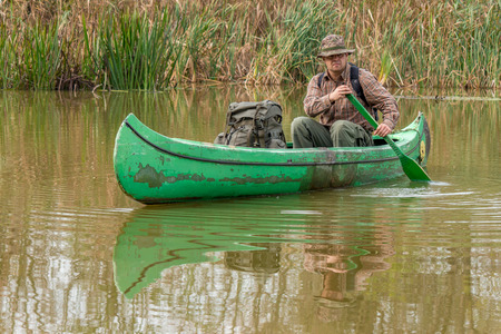 man in old canoe on the riverの写真素材