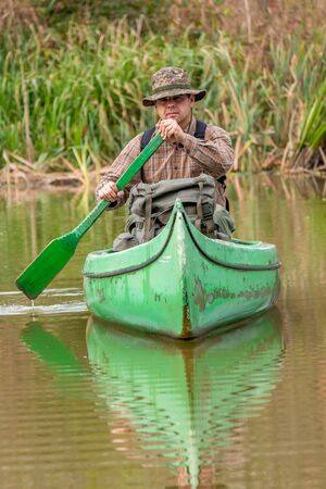 man in old canoe on the riverの写真素材