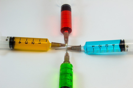 plastic medical syringes containing multicolor solutions with white backgroundの写真素材