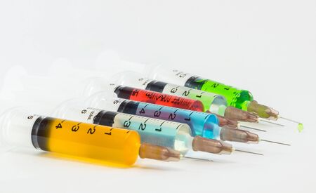 plastic medical syringes containing multicolor solutions with white backgroundの写真素材