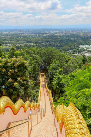 Mae Hia,Chiang Mai,Northern Thailand on Septemmber 13,2019:Golden colored Naga serpents guard the stairs on both sides of the stairway from the ground to Wat Phra That Doi Kham.のeditorial素材