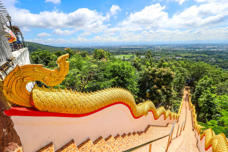 Mae Hia,Chiang Mai,Northern Thailand on Septemmber 13,2019:Golden colored Naga serpents guard the stairs on both sides of the stairway from the ground to Wat Phra That Doi Kham.のeditorial素材