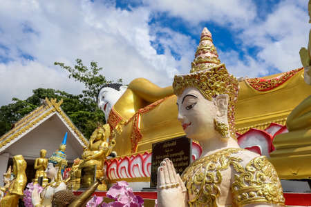 Mae Hia,Chiang Mai,Northern Thailand on Septemmber 13,2019:The figure of a deva clasping hands in token of worship in front of Reclining Buddha Statue at Wat Phra That Doi Kham.のeditorial素材