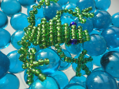 Frog of beads on blue stones background の写真素材