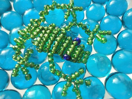 Frog of beads on blue stones background の写真素材