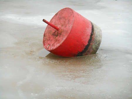 Frozen lake shore and red floatの写真素材