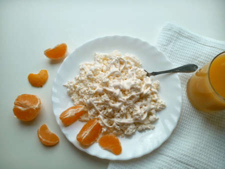 Cottage cheese,tangerine cloves and orange juice on a white backgroundの素材