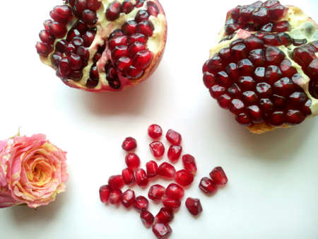 Red pomegranate seeds vitamin and rose flower on a white beautiful backgroundの素材