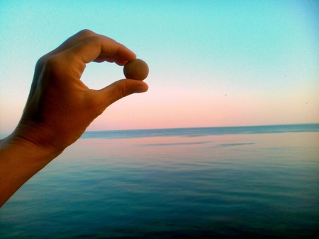Stone in the hand sea and blue sky backgroundの素材