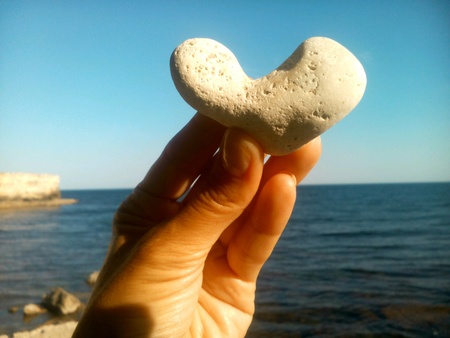 Stone heart in the hand sea and blue sky backgroundの素材