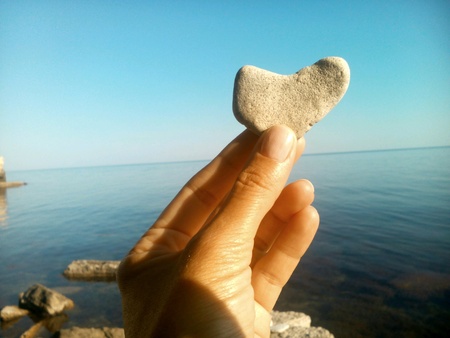 Landscape stone heart in the hand sea and blue sky backgroundの素材