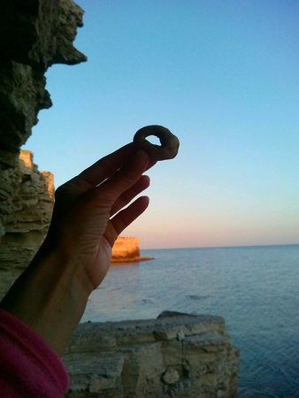A stone with a hole in hid hand sea rock and blue sky backgroundの素材