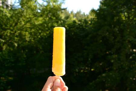 Banana ice cream in the hand on a green summer background