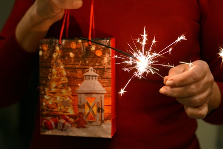 Christmas time gift and bengal light in the female hands