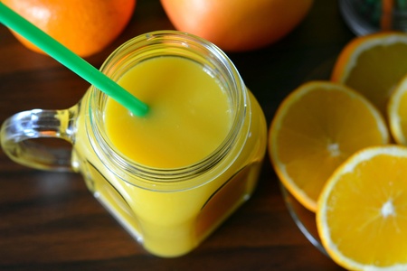 Orange juice and fruits on a wood background