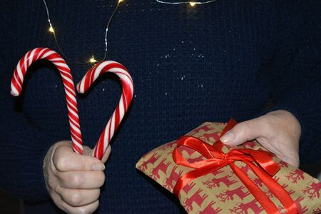 Christmas and New year gift and candy in the female hands dark backgroundの素材