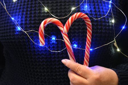Christmas and New year red candy in the female hand light dark backgroundの素材