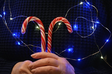 Christmas and New year red candy in the female hands light dark backgroundの素材
