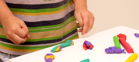little boy playing with clay dough, education and daycare conceptの写真素材