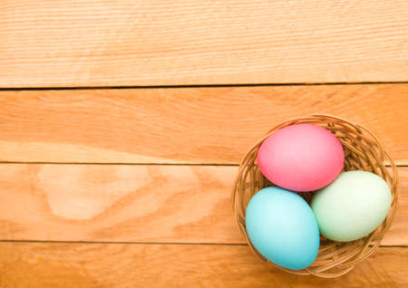 Easter eggs in a wicker basket on a wooden backgroundの写真素材